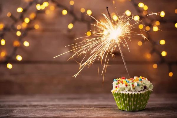 Cupcake met sparkler op oude houten achtergrond Rechtenvrije Stockafbeeldingen