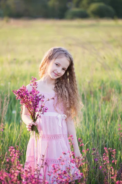Linda menina com flores ao pôr do sol ao ar livre — Fotografia de Stock