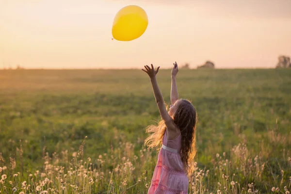 Glad tjej med ballong vid solnedgången — Stockfoto