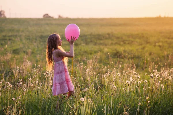 Menina feliz com balão ao pôr do sol — Fotografia de Stock