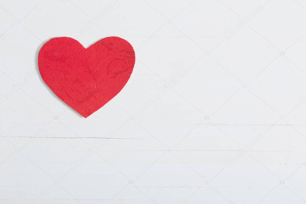 red paper heart on white wooden background