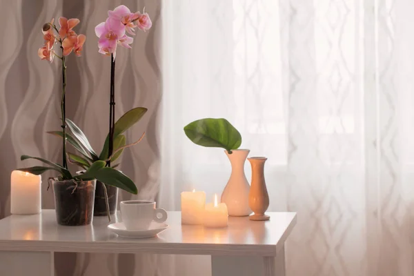 Орхидеи, чашки, свечи на столе в комнате — стоковое фото
