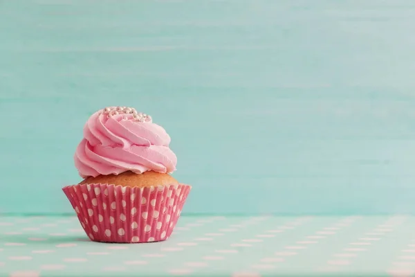 Pink cupcake on blue wooden background — Stock Photo, Image