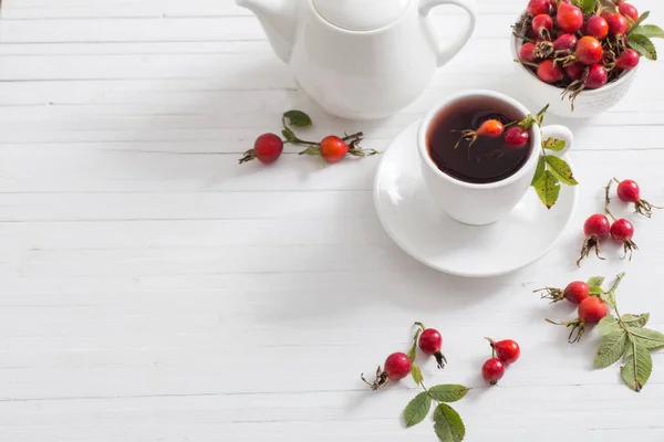 El té con las bayas del escaramujo sobre el fondo de madera — Foto de Stock