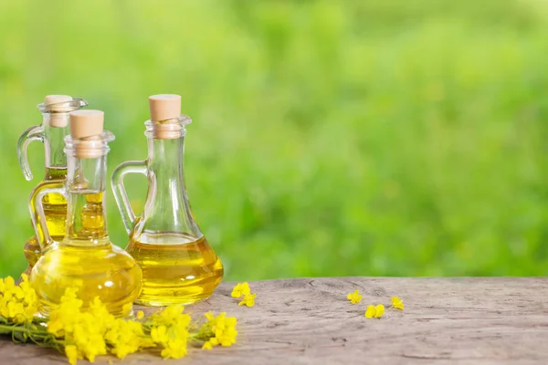 rapeseed oil (canola) and rape flowers on wooden table