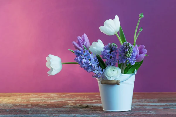 Spring flowers in bucket on pink background — Stock Photo, Image