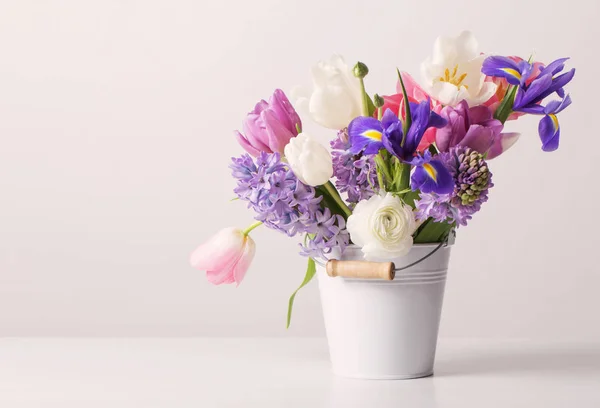 Frühlingsblumen im Eimer auf weißem Hintergrund — Stockfoto