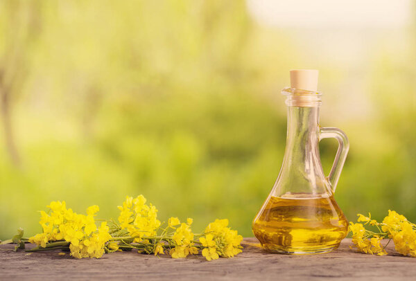 rapeseed oil (canola) and rape flowers on wooden table