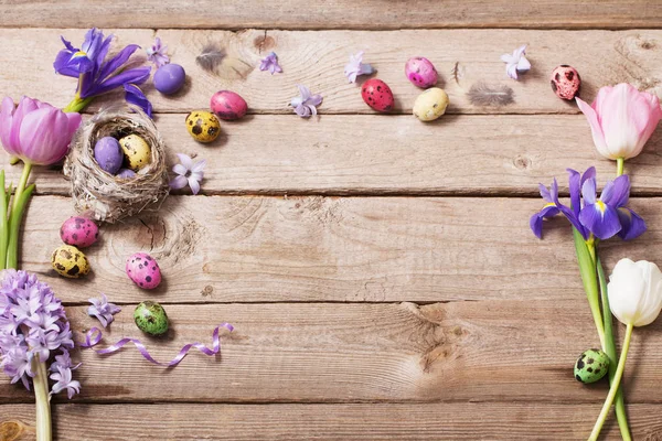 Пасхальные яйца с весенними цветами на фоне дерева — стоковое фото
