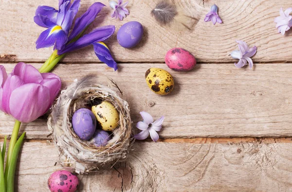 Пасхальные яйца с весенними цветами на фоне дерева — стоковое фото
