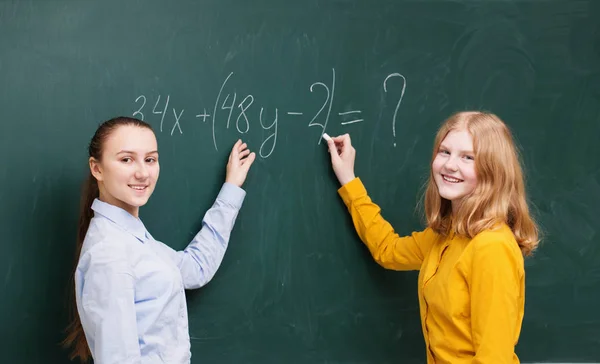 Dos chicas en la pizarra en una clase de matemáticas — Foto de Stock