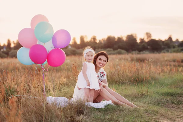 Lycklig mor och dotter med ballonger utomhus — Stockfoto