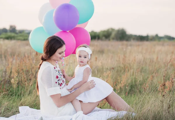 Lycklig mor och dotter med ballonger utomhus — Stockfoto