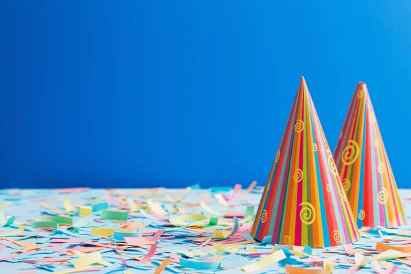 Doğum günü şapkası ve mavi zemin üzerine konfeti — Stok fotoğraf