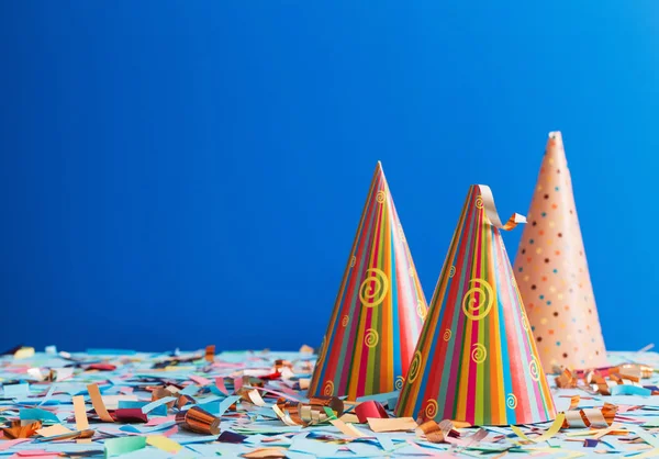 Chapéu de aniversário e confete no fundo azul — Fotografia de Stock