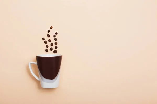 Grains de café et une tasse sur un fond clair — Photo