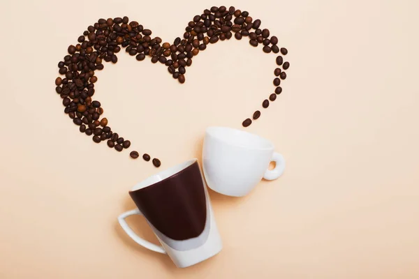 Two cups with coffee beans on light background — Stock Photo, Image