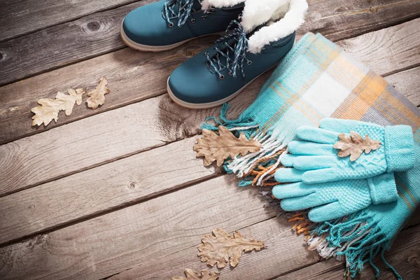 Winter shoes, gloves, scarves  on old wooden background