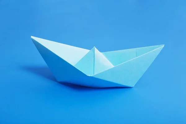 Бумажная лодка на фоне голубой бумаги — стоковое фото
