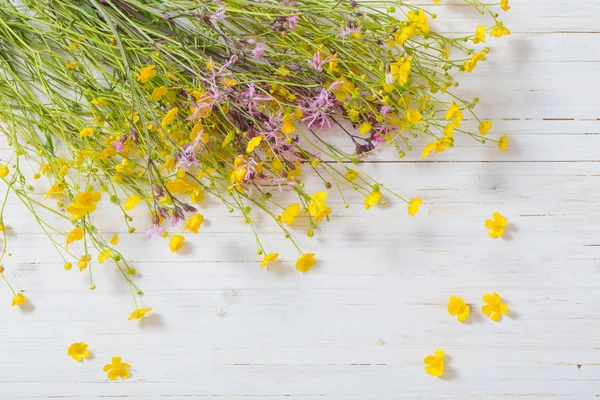 Beyaz ahşap zemin üzerine sarı ve pembe çiçekler — Stok fotoğraf