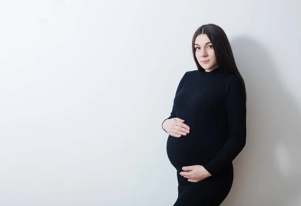 Pregnant women in black dress on background white wall — Stock Photo, Image