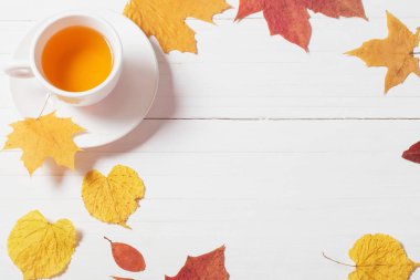 Ahşap arka planda sonbahar yapraklı bir fincan çay.