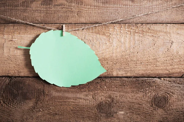 green paper leaf on wooden background