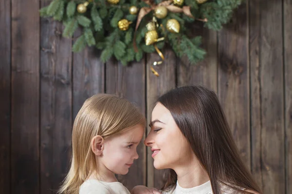 Mor och dotter på julgran på en trä bakgrund — Stockfoto