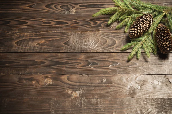 Tannenzweige und Zapfen auf dunklem altem Holzgrund — Stockfoto