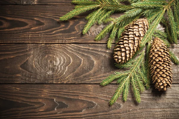 Tannenzweige und Zapfen auf dunklem altem Holzgrund — Stockfoto