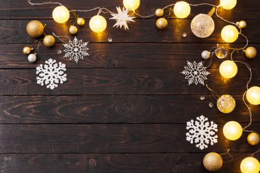 Karanlık ahşap arka planda ışıkları olan Noel süslemeleri.