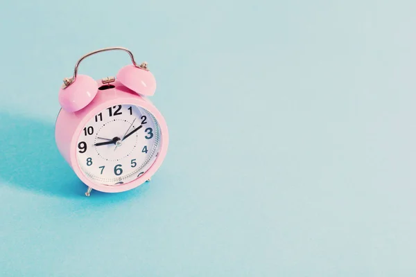 Pink alarm clock on blue background — Stock Photo, Image