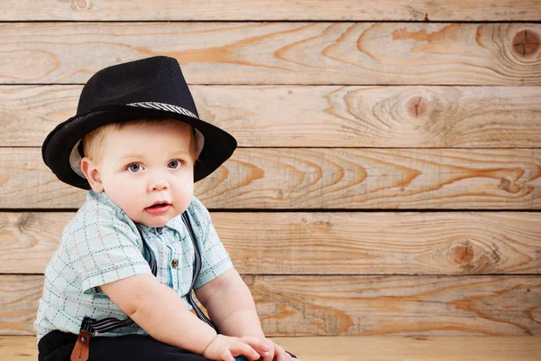 Siyah şapkalı bebek, gömlek ve pantolon şortu ahşap sırt çantasında. — Stok fotoğraf
