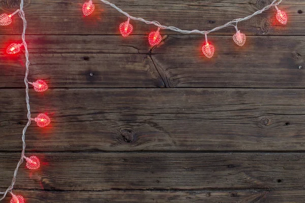 Heart-shaped garland on old dark wooden background — Stock Photo, Image