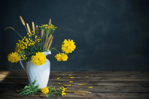 Gelbe Blüten in weißem Krug auf dunklem Hintergrund — Stockfoto