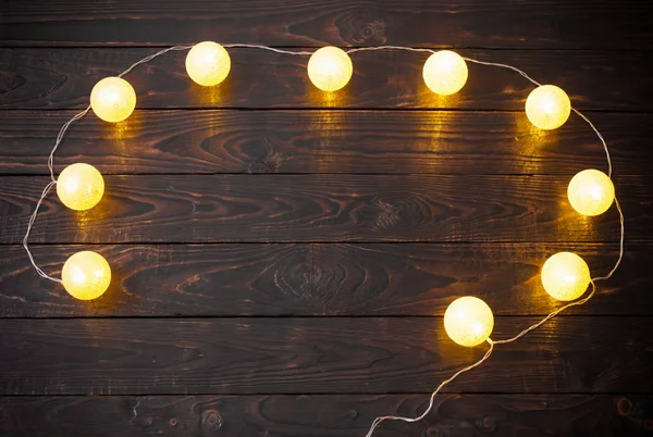 Christmas golden lights on dark wooden background — Stock Photo, Image