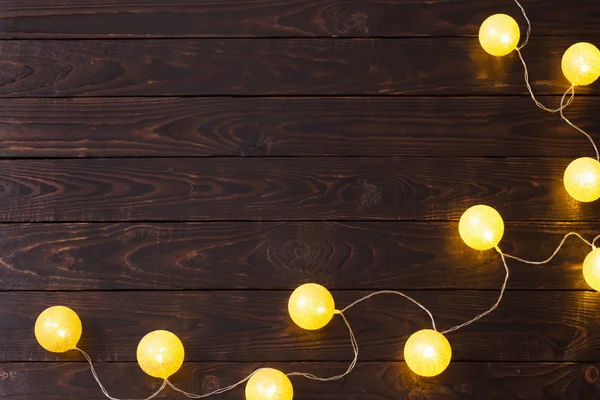 Weihnachten goldene Lichter auf dunklem Holzhintergrund — Stockfoto