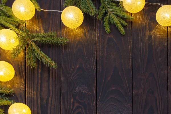 Weihnachtsbeleuchtung mit Tannenzweigen auf dunklem Holzhintergrund — Stockfoto