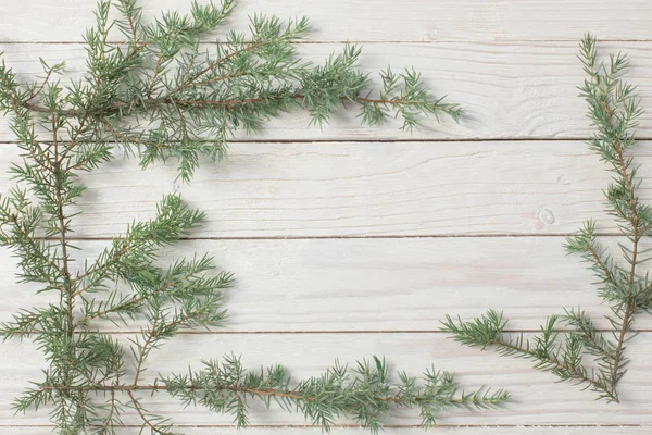 Wacholderzweige auf weißem Holzgrund. Weihnachten und Neujahr — Stockfoto