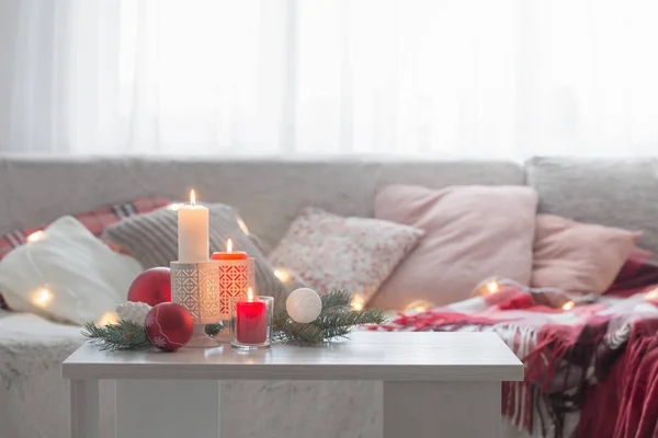 Vánoční dekorace se svíčkami a míčky na bílém stole uvnitř — Stock fotografie