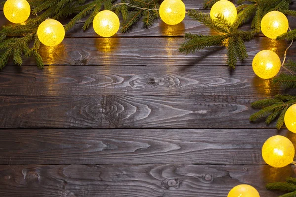 Weihnachtsbeleuchtung mit Tannenzweigen auf dunklem Holzhintergrund — Stockfoto