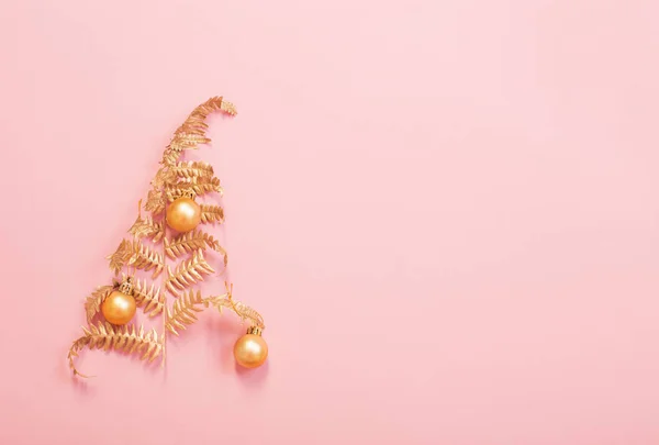 Weihnachtsbaum aus bemalten goldenen Blättern Farn auf rosa Papierrücken — Stockfoto
