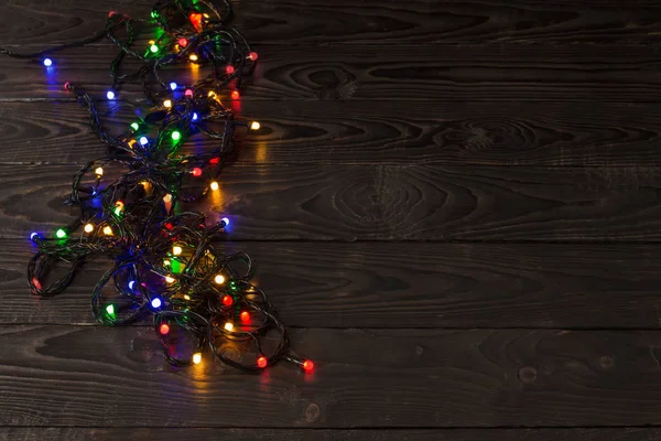 Elektrische slinger met veelkleurige gloeilampen op een houten branding — Stockfoto