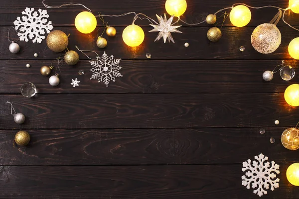 Karanlık ahşap arka planda ışıkları olan Noel süslemeleri.