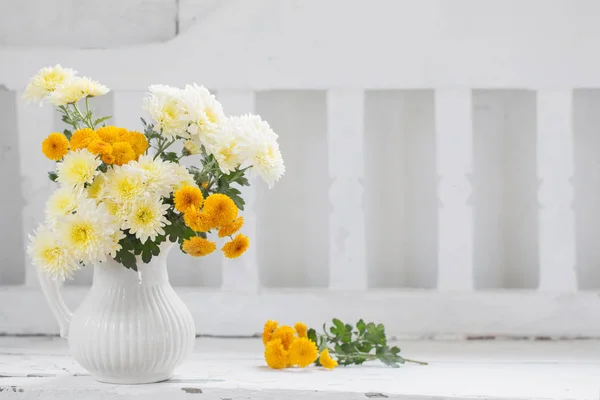Crisantemos amarillos en jarra en banco de madera blanco viejo — Foto de Stock
