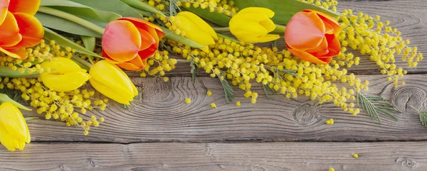 Tulipani e mimosa su sfondo scuro in legno antico — Foto Stock