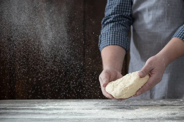 Mãos cozinhando massa no fundo de madeira escura — Fotografia de Stock