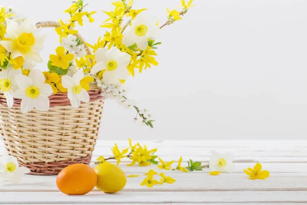 Pisanki z wiosennymi kwiatami na białym drewnianym stole — Zdjęcie stockowe
