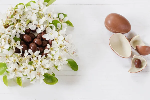 Schokolade-Ostereier mit Frühlingsblumen auf Holzgrund — Stockfoto
