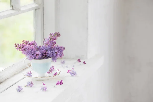 Ramo de lilas en taza de cerámica en el viejo alféizar de la ventana blanca — Foto de Stock